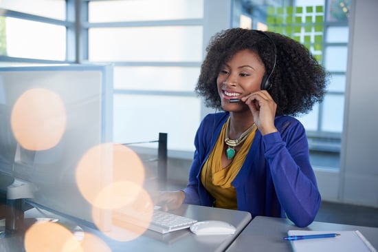 Portrait of a smiling customer service representative with an afro at the computer using headset-3