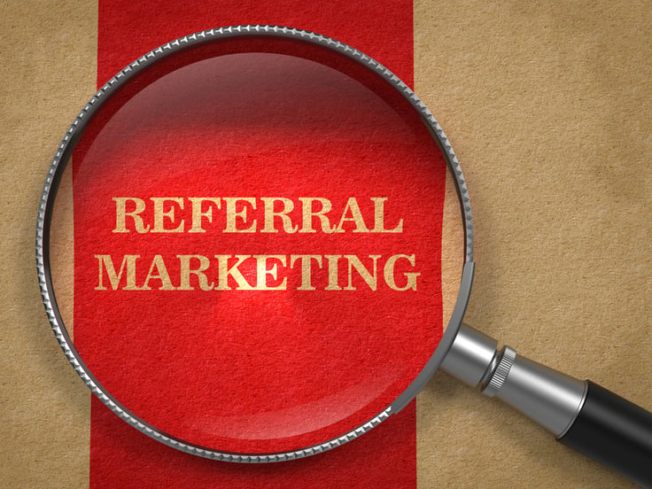 Referral Marketing Concept. Magnifying Glass on Old Paper with Red Vertical Line Background.